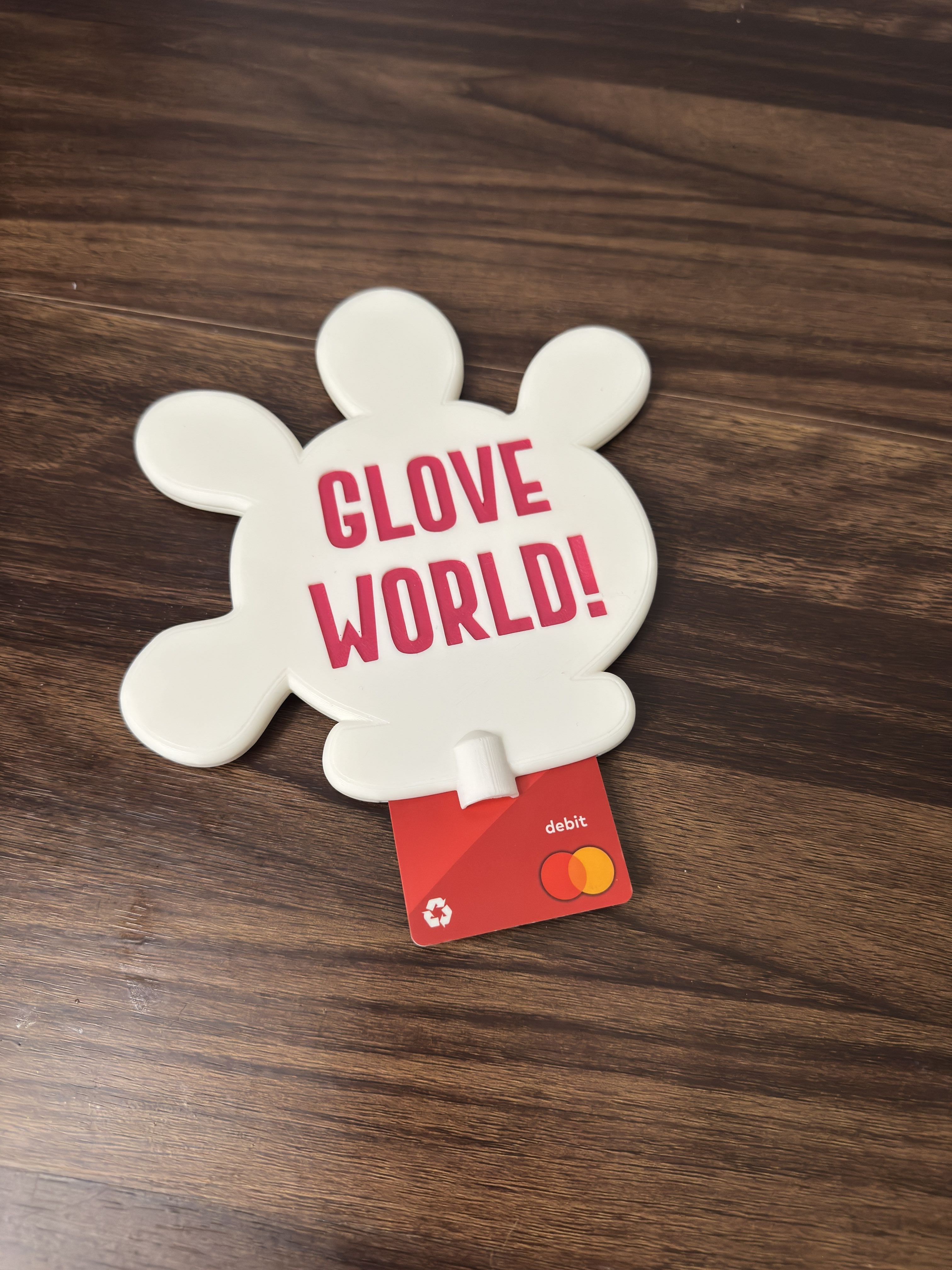 White glove-shaped object with 'Glove World!' text and a red card on a wooden surface