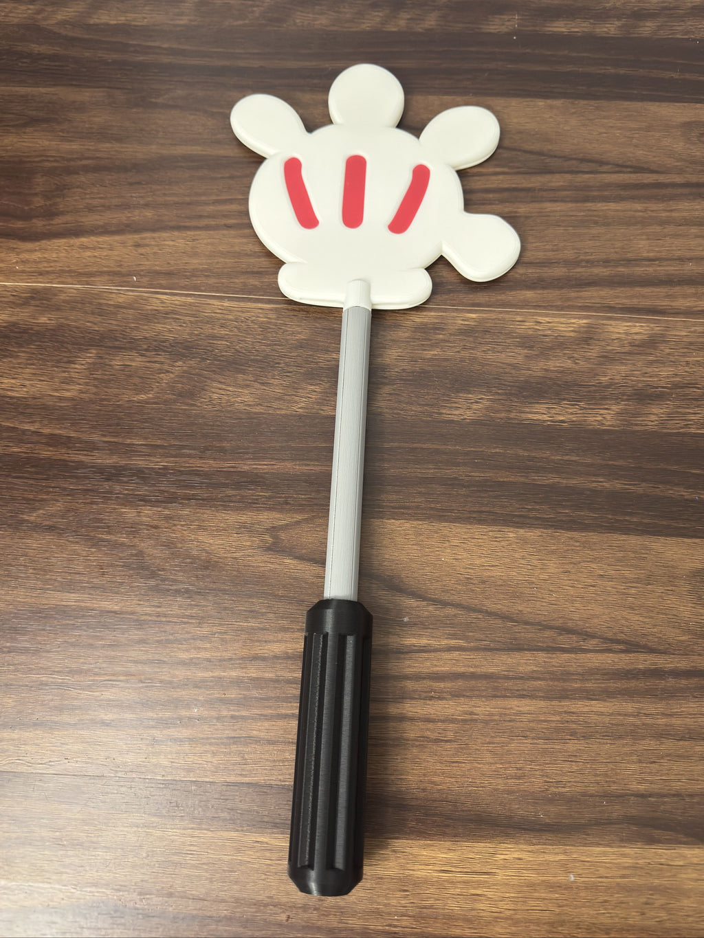White glove with a handle and with red accents on a wooden surface